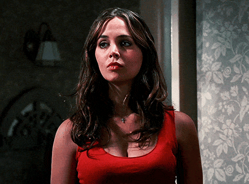 a woman wearing a red tank top with a cross necklace