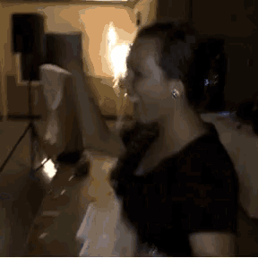 a woman in a black shirt is dancing in a room