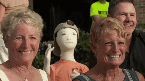 a group of people are posing for a picture with a mannequin wearing an orange shirt that says ' abercrombie ' on it