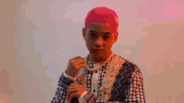 a young man with red hair is wearing a plaid shirt and pearls .