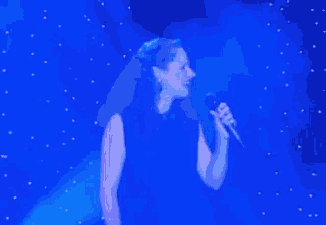 a woman singing into a microphone on a stage