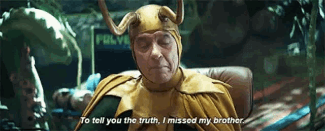 a man dressed as loki is sitting in a chair and talking to another man .
