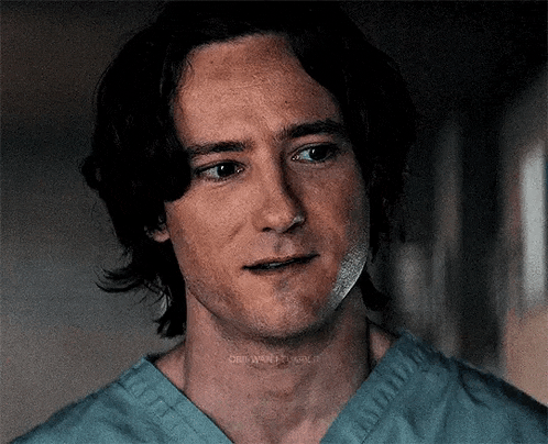 a close up of a man 's face in a scrub top .