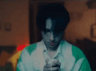 a man in a green and white shirt is holding a white object in his hand .