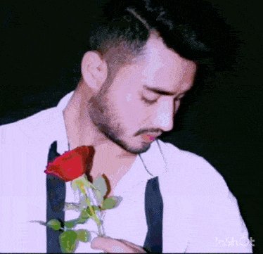a man is holding a red rose in his hand .