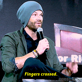 a man speaking into a microphone with the words " fingers crossed " on the bottom