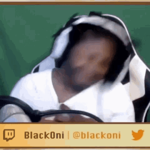 a man wearing headphones is sitting in a chair and looking at his phone .