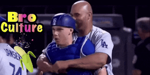 a baseball player wearing a la jersey is hugging his coach