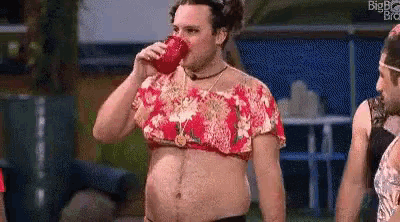 a man is drinking from a red cup while wearing a bikini top .