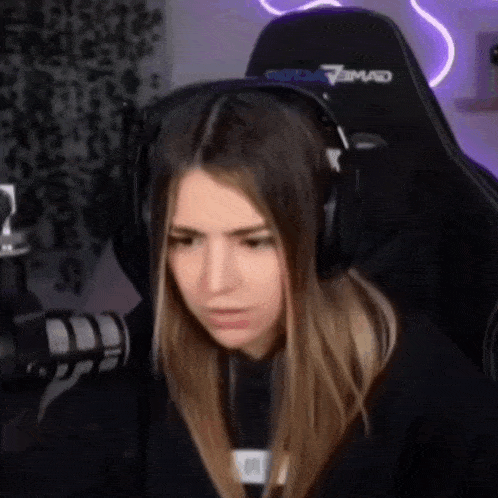 a girl wearing headphones is sitting in a gaming chair .