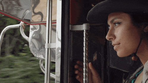 a woman wearing a hat looks out of a window