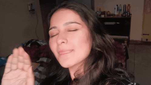 a woman with her eyes closed and her hand up