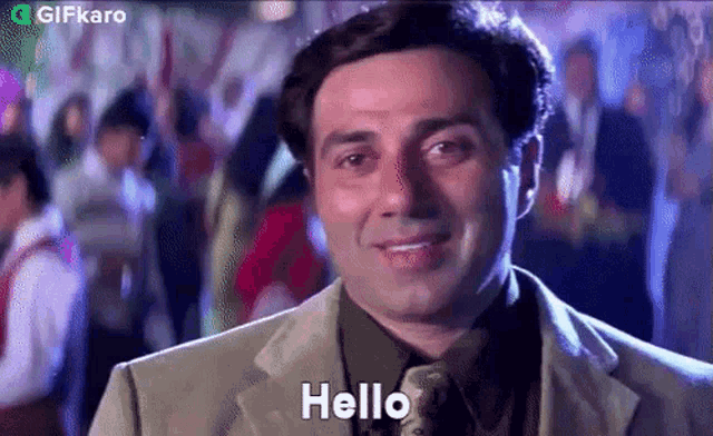 a man in a suit and tie is standing in front of a crowd and saying hello .