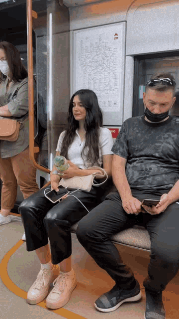 a man and a woman are sitting on a train with a map on the wall behind them