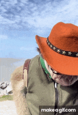 a man wearing an orange hat and glasses looks down at something