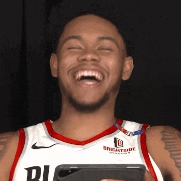 a man in a brightside jersey laughs while holding a cell phone