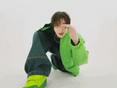 a person wearing a green jacket and blue jeans is kneeling down