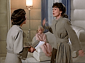 two women are standing in a room and one is holding a clipboard