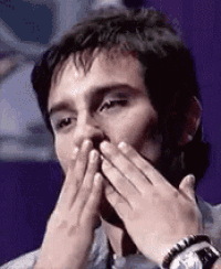 a man is covering his mouth with his hands and a watch on his wrist .