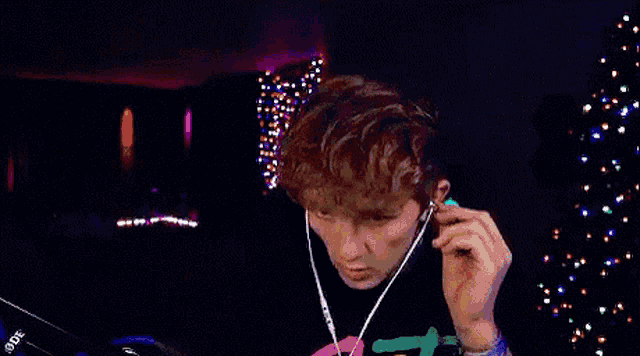 a man wearing headphones is sitting in front of a christmas tree in a dark room .