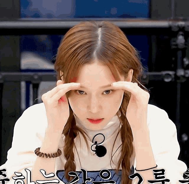 a woman covering her eyes with her hands in front of a sign that says ' a ' on it