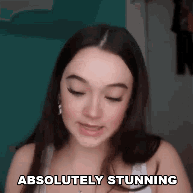 a woman says she is absolutely stunning in front of a blue wall
