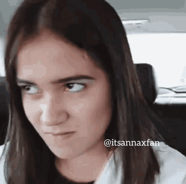 a woman is making a funny face while sitting in the back of a car .