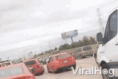 a red car is driving down a highway in a traffic jam .