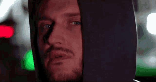 a man with a beard is wearing a black hooded sweatshirt .