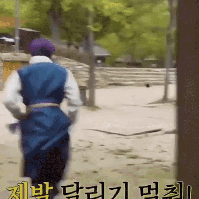 a man in a purple hat is walking in a park with chinese writing on the ground