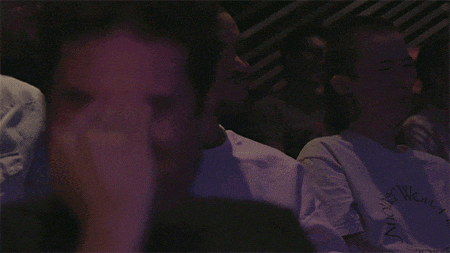 a man in a black shirt is laughing while sitting at a table
