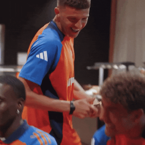 a man wearing a blue and orange adidas shirt