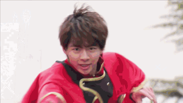 a young man in a red cape is standing in front of a tree .