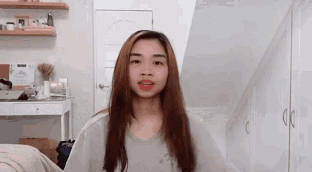 a young woman with long hair is standing in front of a white door in a room .