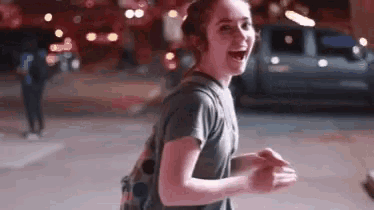 a young woman with a backpack is laughing on the street .