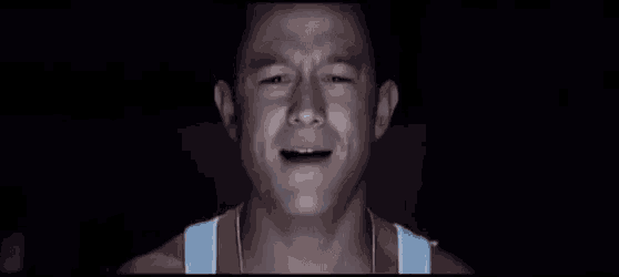 a man in a white tank top is crying with his mouth open .