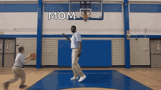 a man is playing basketball with a child and the word mom is on the wall