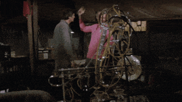 a man in a pink shirt is being held by another man in a dark room