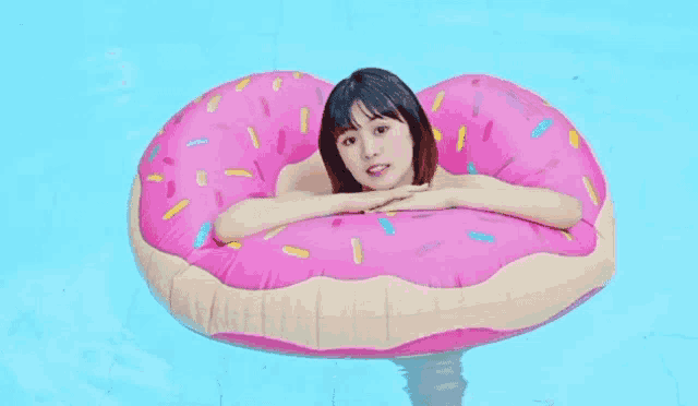 a woman is floating on an inflatable doughnut in a pool .