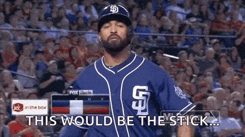 a man in a blue baseball uniform is standing in front of a crowd and says this would be the stick .