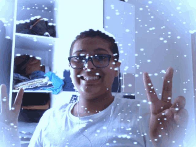 a girl wearing glasses giving a peace sign with snow falling around her