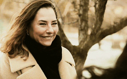 a woman wearing a fur coat and scarf smiles for the camera