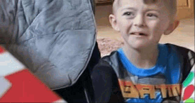 a young boy in a blue shirt is crying while sitting on a couch .