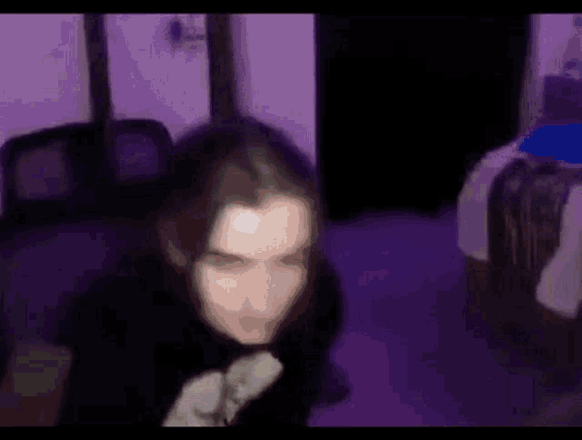 a blurry picture of a person sitting in a room with purple lights .