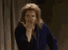 a man with long hair is making a wink sign with his finger .
