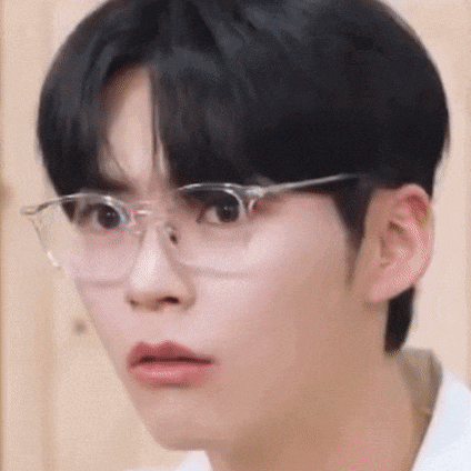 a young man wearing glasses is making a funny face .