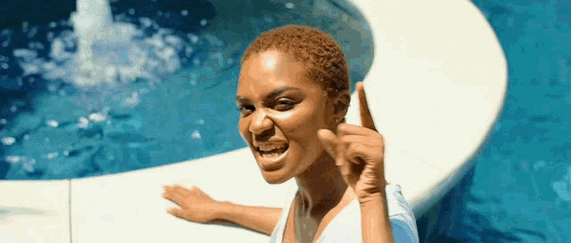 a woman is sitting in front of a swimming pool and pointing up
