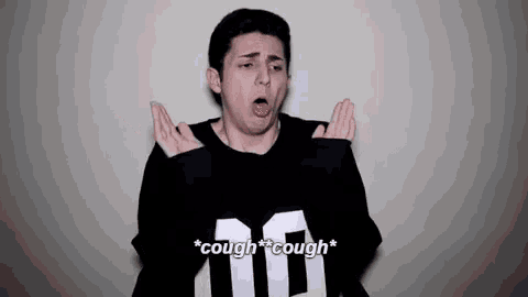 a young man in a black and white shirt is coughing and making a funny face .