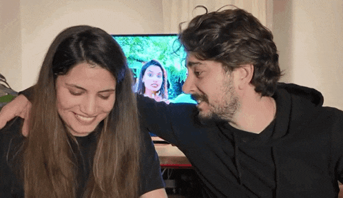 a man and a woman are looking at each other in front of a television