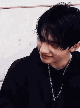 a close up of a young man wearing a black hoodie and a silver necklace .